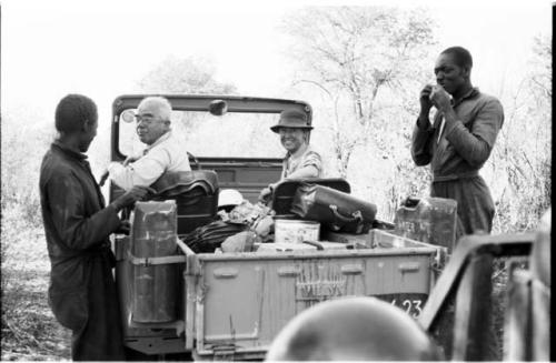 Laurence Marshall and Lorna Marshall sitting in the expedition Jeep, with two men present