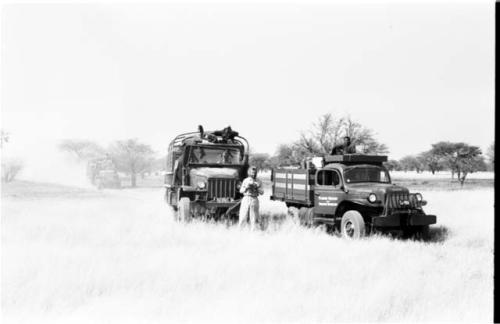 Two expedition trucks, with Daniel Blitz holding a camera in front of them