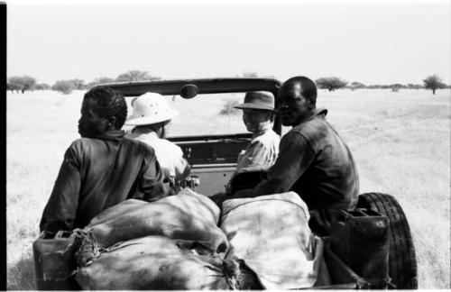 Laurence Marshall sitting behind the wheel in the expedition Jeep, with Lorna Marshall, and other two men present