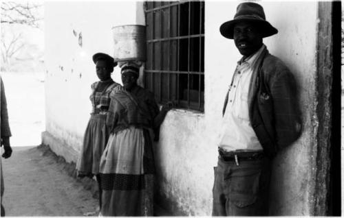 Man and two girls standing leaning against the wall of a store at Sehitwe