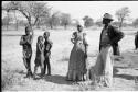 Man in European clothes, a woman in Herero dress, and three boys, full figure standing