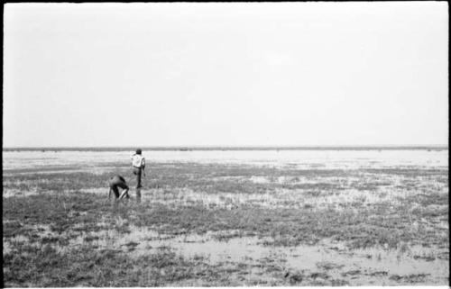 Elizabeth Marshall Thomas and John Marshall, who is holding a gun in his hand, wading in Lake Ngami