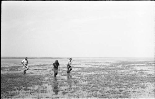 Casper Kruger, Elizabeth Marshall Thomas, and John Marshall, who is holding a gun in his hand, wading in Lake Ngami