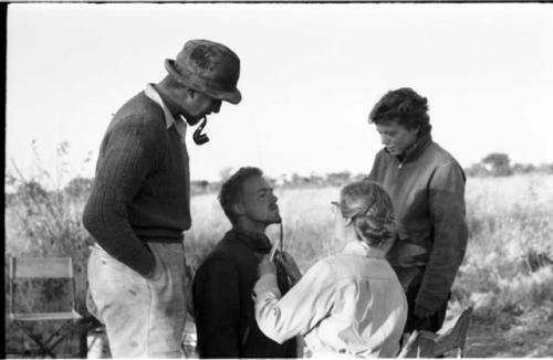 Lorna Marshall trimming John Marshall's beard, with Casper Kruger and Elizabeth Marshall Thomas advising
