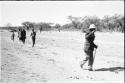 Man in a pith helmet walking, followed by a group of people