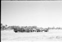 People standing next to expedition members near trucks, distant view