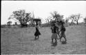 Three women walking with goods piled on their heads and with a girl