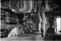 Interior of a trader's store at Sehitwe, with a man standing behind a counter