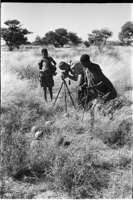 /Twikwe and DaSi!Na standing beside John Marshall while he films