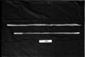 Two digging sticks on a black background, with a ruler for measurement