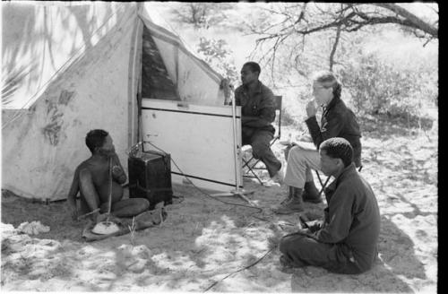 Oukwane playing the musical bow while Lorna Marshall, Kernel Ledimo, and Dabe record