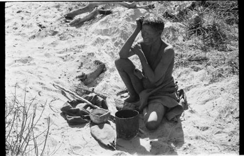 //Kuǂtera sitting in the sand, her belongings spread before her