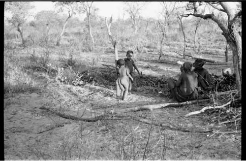 /Ti!kay, a woman, and two children under a tree