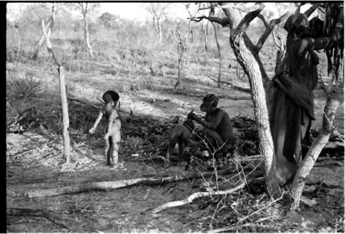 /Ti!kay and two children beneath a tree