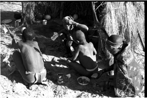 Four people sitting around a fire, seen from behind