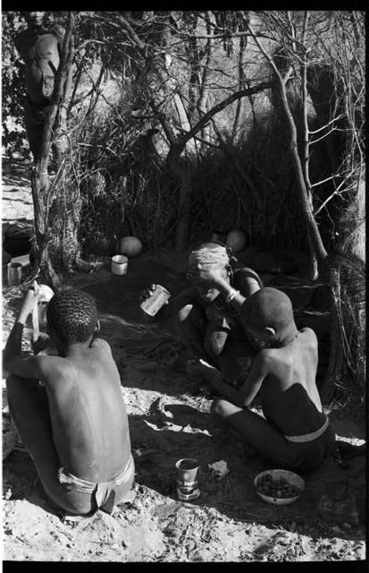 Three people sitting around a fire, seen from behind