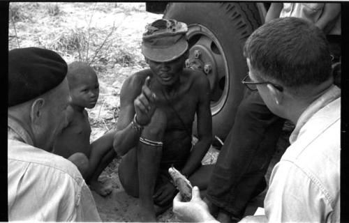 "/Gao Overalls" and a boy sitting with O.P.M. Prozesky and Nicholas England sitting across from him, seen from behind