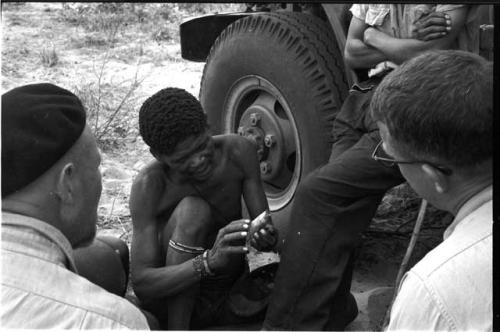 "/Gao Overalls" holding a bird sitting with O.P.M. Prozesky and Nicholas England sitting across from him, seen from behind