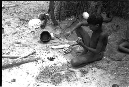 Boy, "/Gao Overall's" son, sitting holding a cocoon