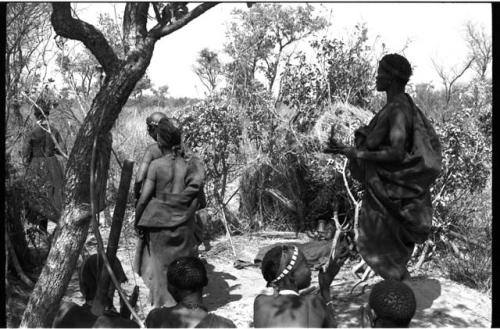Three women standing and four women sitting, performing a menstruation ceremony