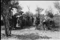 Group of women performing a menstruation ceremony, an expedition member recording sound; a man bent over, seen from behind