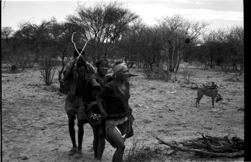 N//aba, !Xoa, and a man holding eland horns walking counter-clockwise, performing the Eland Dance