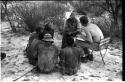 Wilhelm Camm and Nicholas England in chairs interviewing five men sitting on the ground