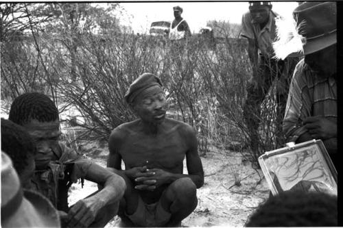 Wilhelm Camm in a chair with a sound recording machine interviewing five men