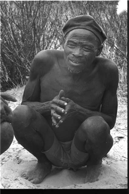 Portrait of a man wearing a hat, sitting with his hands together