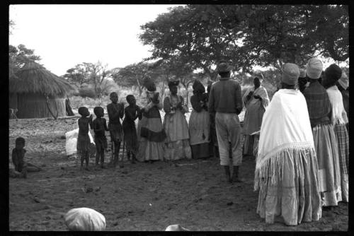 Group of women clapping, standing in a line with Kangengi standing in the middle, preparing to sing