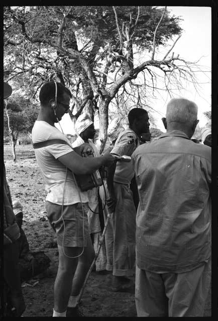 Nicholas England recording sound, Laurence Marshall standing next to him; group of people standing around them