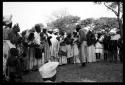 Women standing in a line singing with Judas Kangengi standing in the middle