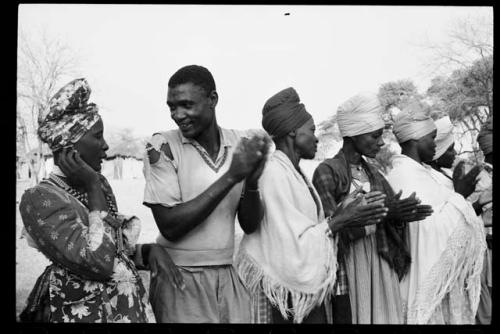 Ananias standing in a line with women who are clapping