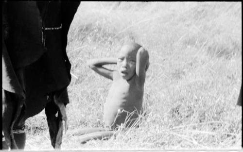 Child sitting, and the legs of a woman standing