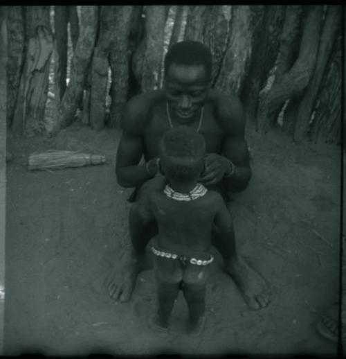 Man sitting with a child standing in front of him