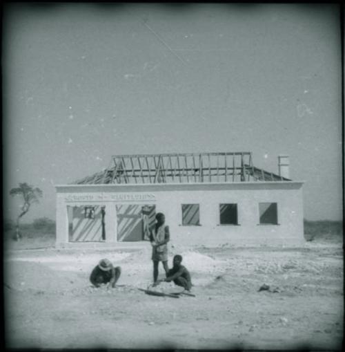 Men sitting and standing in front of a clinic under construction