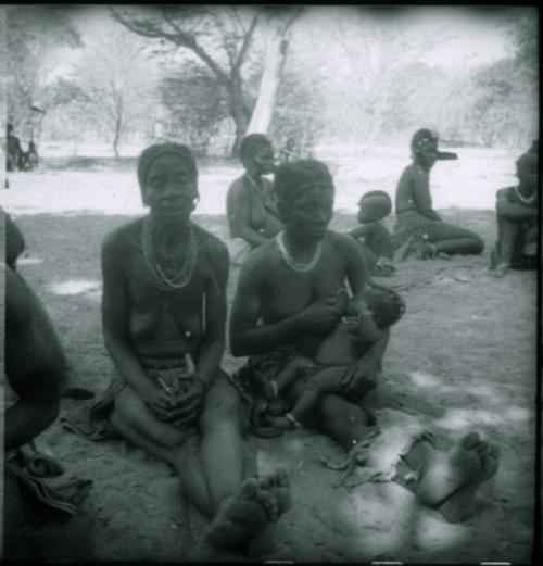 Two women sitting, and one is nursing a child