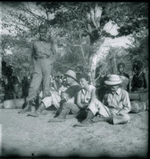 People sitting behind Robert Dyson standing, with Laurence Marshall, Elizabeth Marshall Thomas and Lorna Marshall sitting, showing their insulated boots