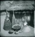 Fish traps, baskets and food in front of a hut