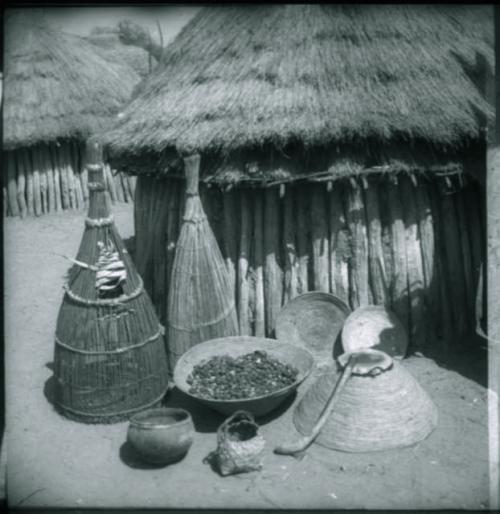 Fish traps, baskets and food in front of a hut