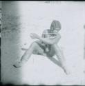 Woman sitting on the ground and playing a musical bow