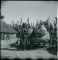 Woman standing in her kraal next to storage baskets