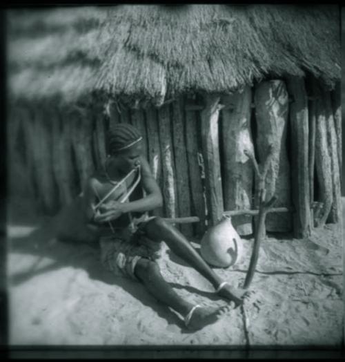 Woman sitting and playing a musical bow