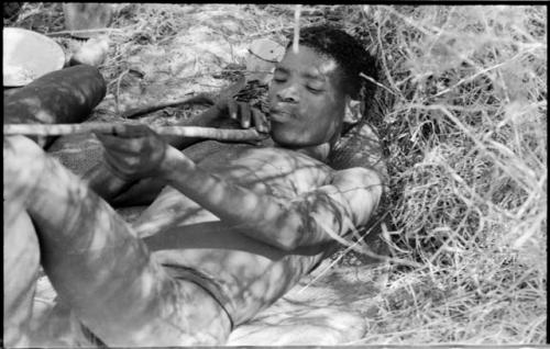 Man reclining and examining a stick