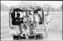 Men sitting in the truck in the water, and John Marshall walking in the water next to it