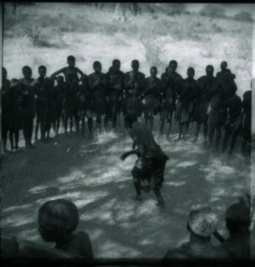 Woman dancing in the center of a circle of women clapping and singing