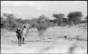 /Gunda and another man standing and looking at animals in the distance, with their backs to the camera