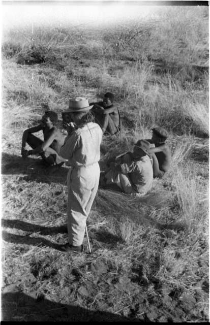 Group of people sitting, with Lorna Marshall standing next to them