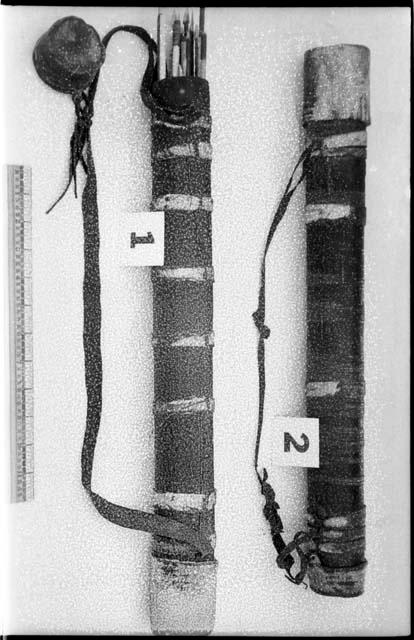 Two quivers; one with arrows inside, one with its cap on, and a ruler for measurement