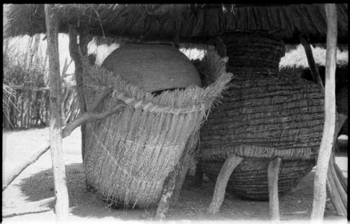 Two storage baskets under a thatched roof